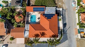 Una vista aerea di una proprietà residenziale con piscina, pannelli solari e tetto in tegole.