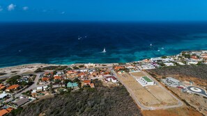 An aerial view of a coastal town with buildings, roads, and boats on the sea. - NEW Modern Cozy Studio Walking Distance to Beach (Noord)