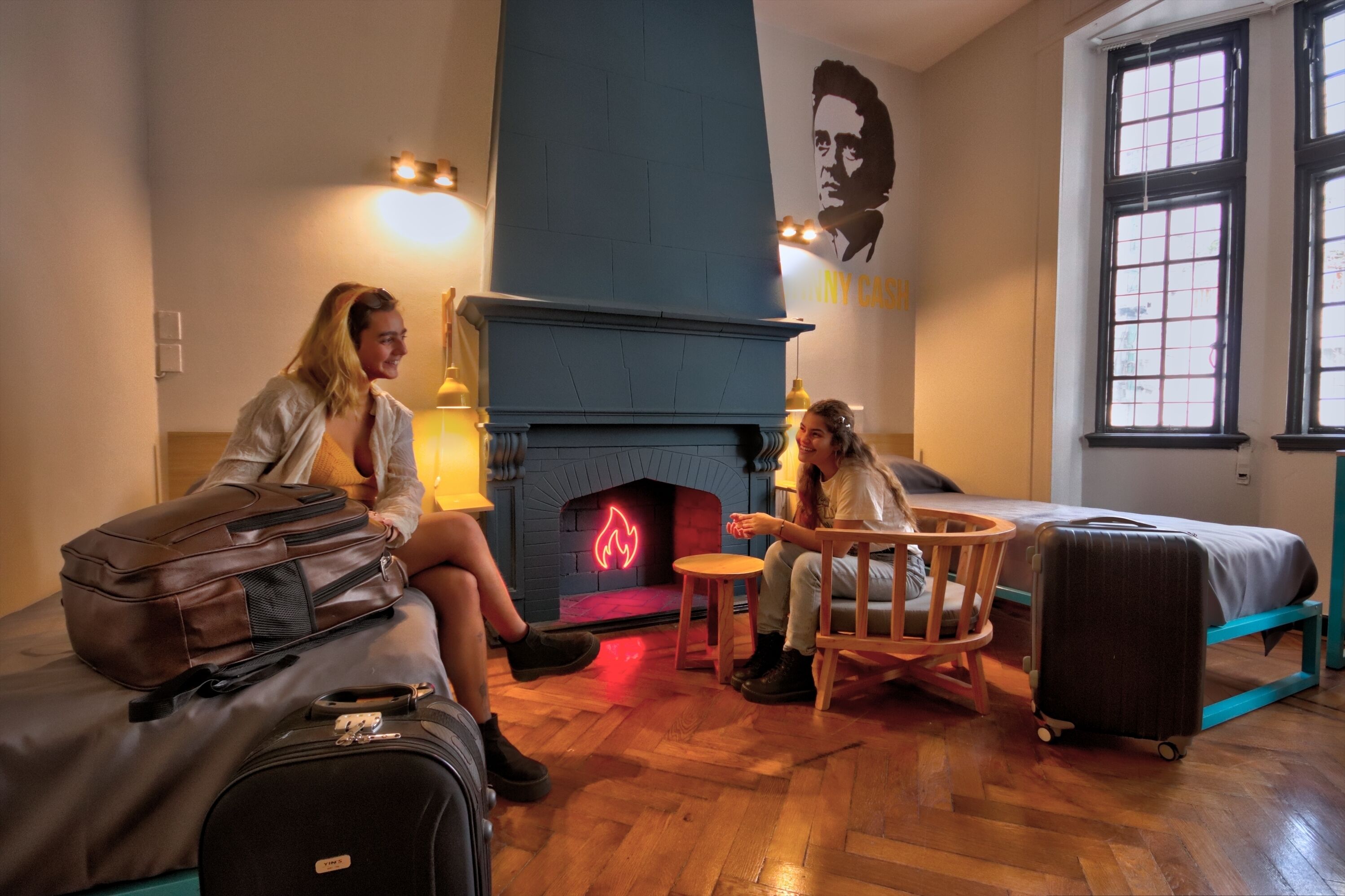 Una habitación con chimenea, cama, sillón y maleta.