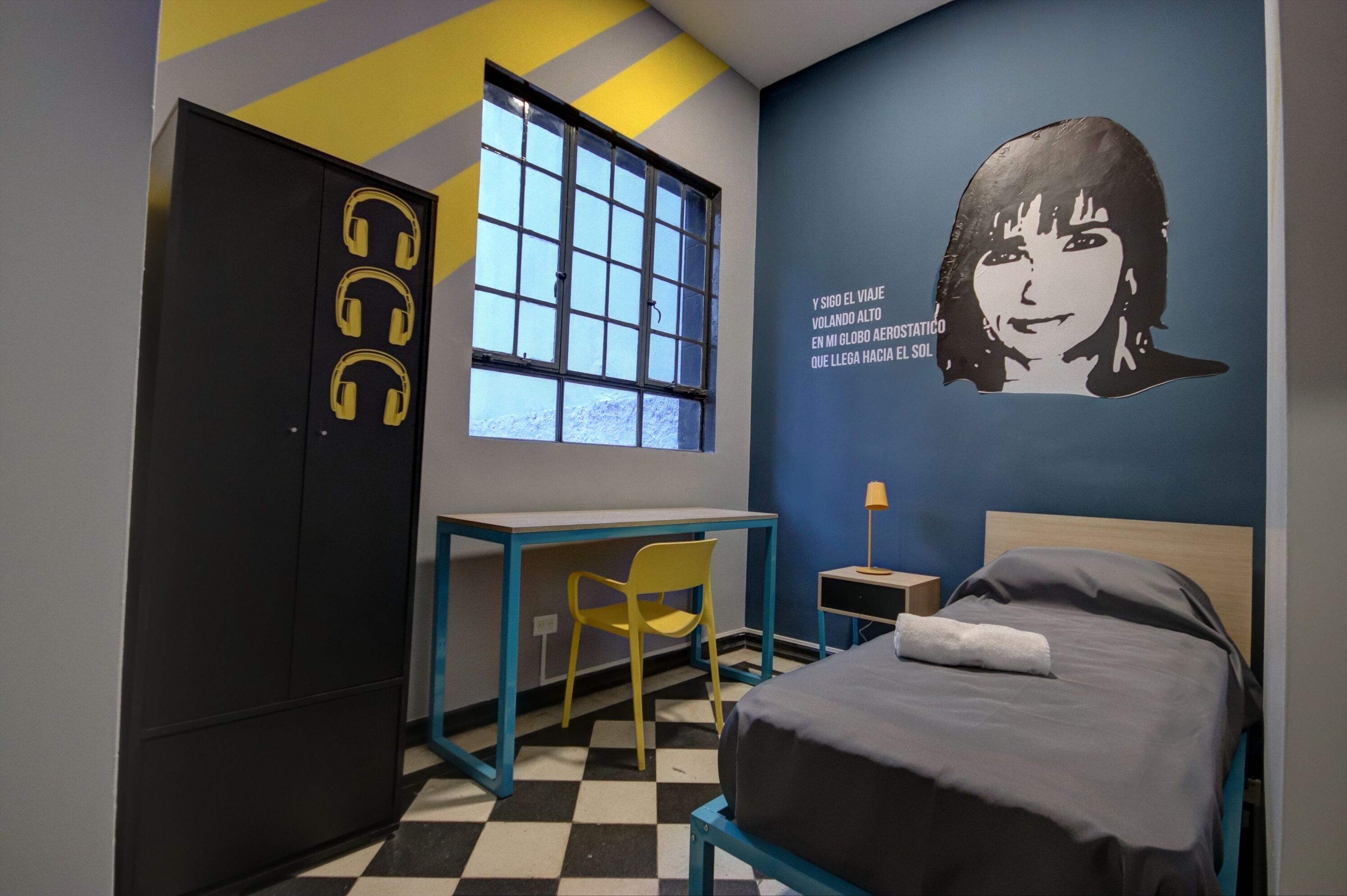 Una habitación con cama, escritorio, silla, armario y ventana.
