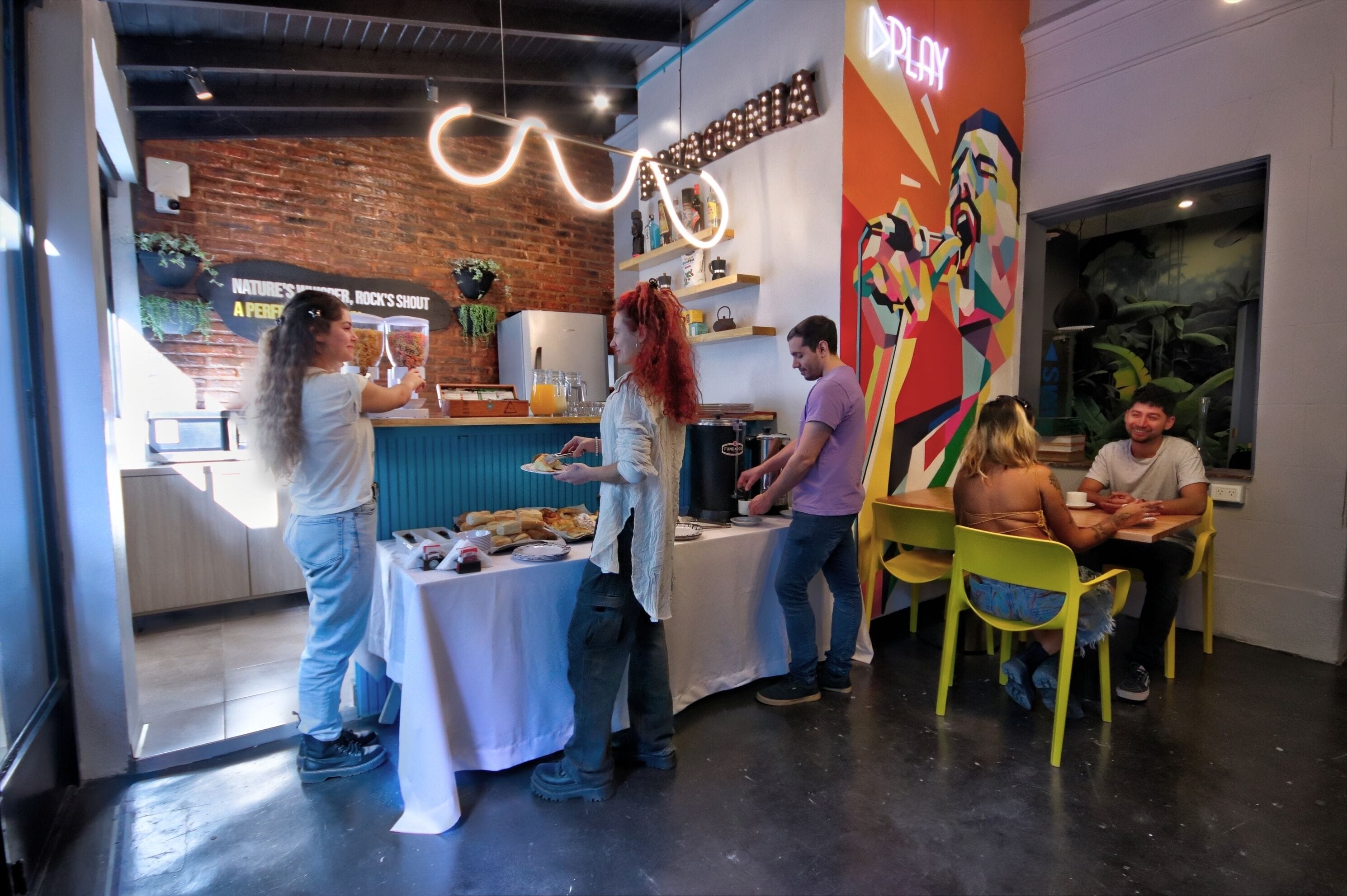 Un restaurante con pared de ladrillo, un letrero de neón y un mural.