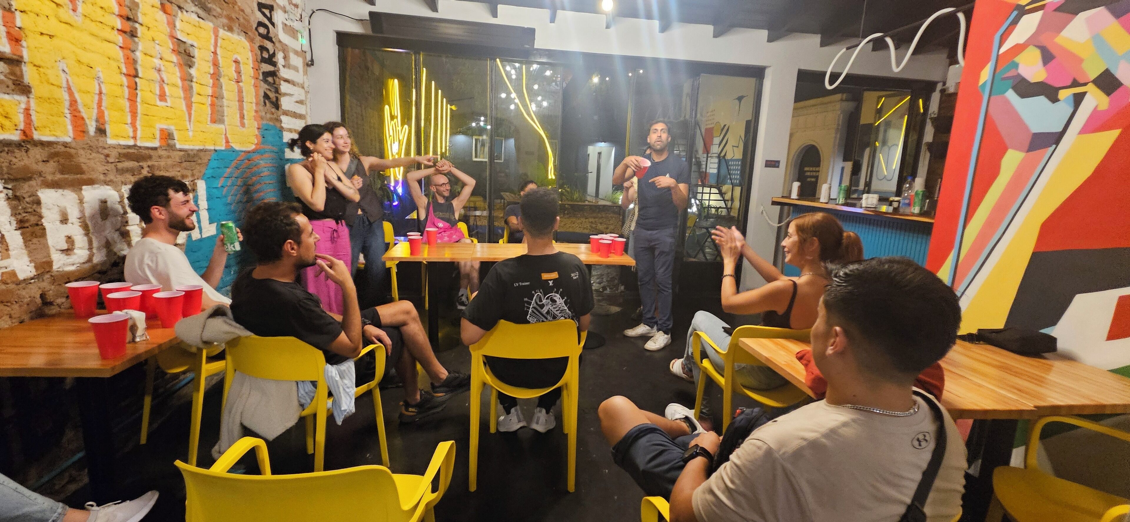 Un groupe de personnes est assis autour d’une table, sur des chaises jaunes, et participe à une discussion.