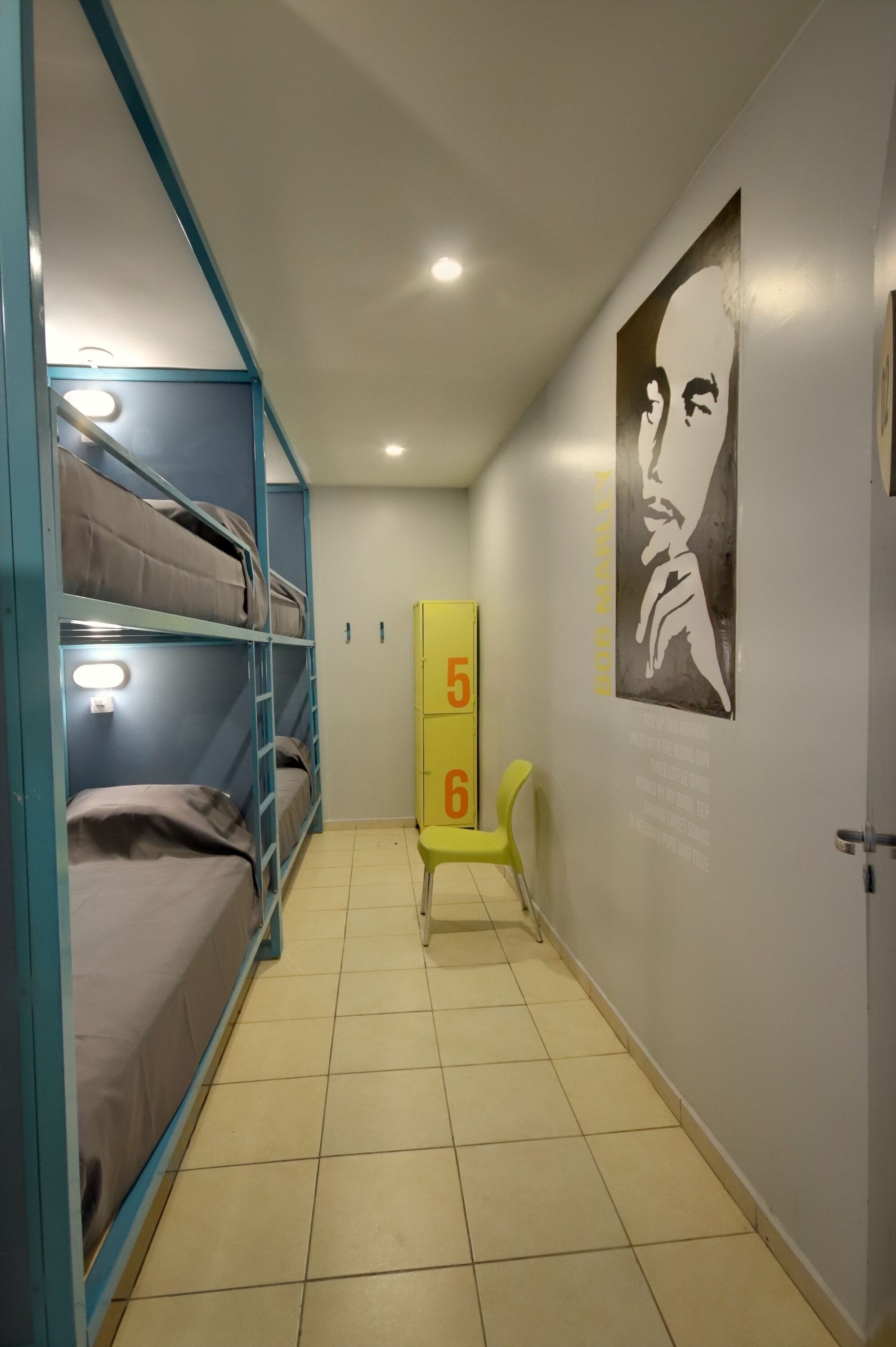 Un pasillo con literas, una silla amarilla y un cartel en la pared.