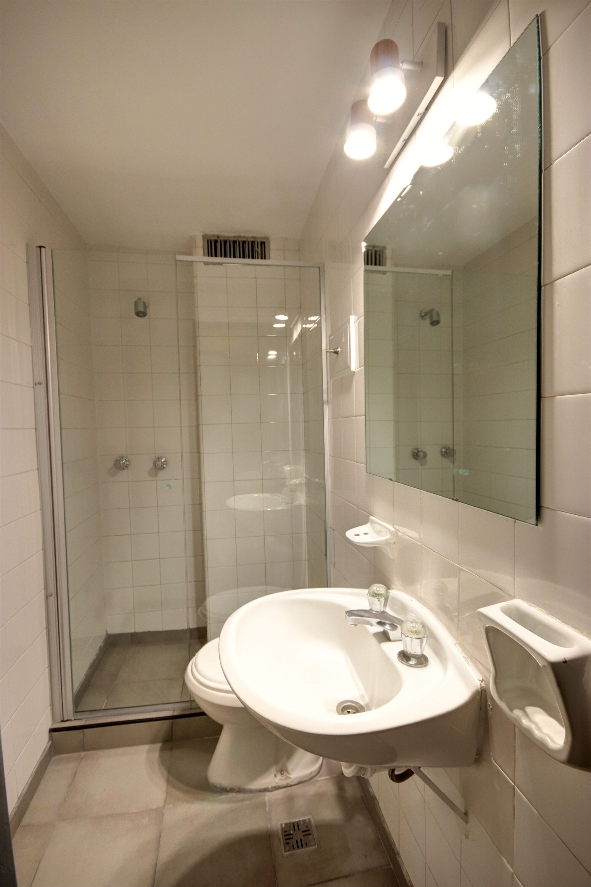 A modern bathroom with a glass-enclosed shower, a white sink, and a large mirror.