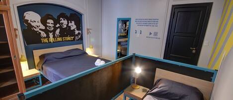 Un dormitorio con una litera, un cartel de The Rolling Stones, un cartel con texto relacionado con la música y una puerta con cerradura.