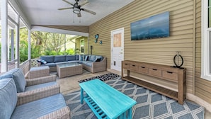 A covered outdoor living area with a ceiling fan, a sectional sofa, a coffee table, and a wooden bench. - Garden House with Pool & Spa (Bradenton)
