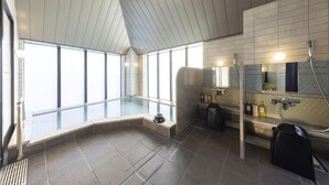 A modern bathroom with a glass-enclosed hot tub, large windows, and a shower area.