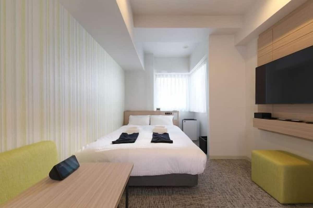 A hotel room with a bed, a TV, a desk, and a chair.
