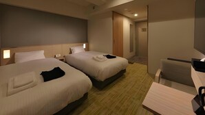 A hotel room with two beds, a desk, a chair, and a TV.