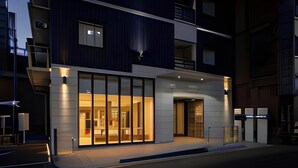 A modern hotel with a glass facade, a visible entrance, and a balcony.