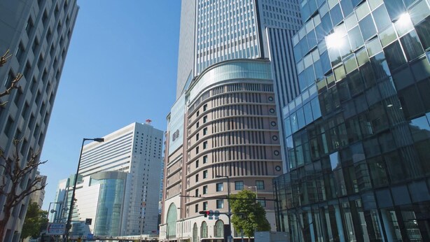 A high-rise urban building with a curved facade, large windows, and a clear sky.