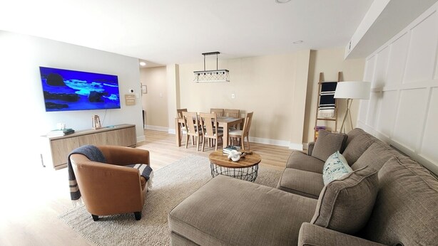 A modern living room with a sofa, a coffee table, a TV, and a dining area with chairs and a table.
