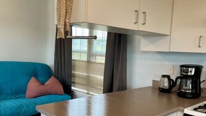 Una cocina compacta con armarios blancos, una encimera, una cafetera y una estufa.