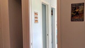 Un dormitorio con una cama, una puerta que da a un pasillo y un cartel en la pared.