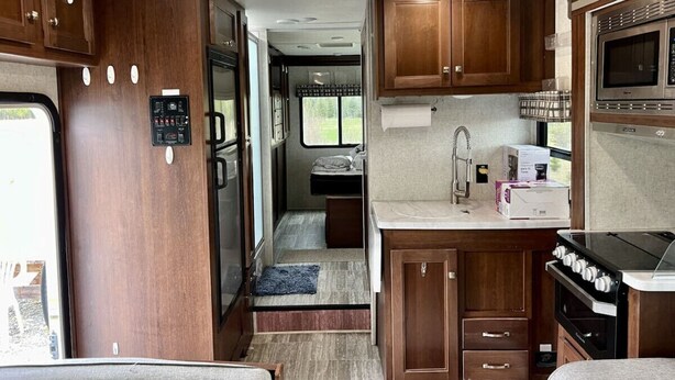 Une cuisine compacte pour camping-car, avec des placards en bois, un four à micro-ondes, une cuisinière et un petit évier.