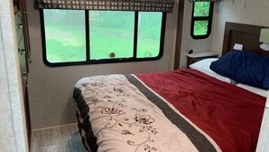 Une chambre à coucher avec un lit, une fenêtre donnant sur un beau paysage, une tête de lit et une table de chevet.