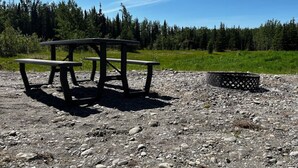 Une table de pique-nique avec des bancs et un foyer, installée dans un espace extérieur rocheux.