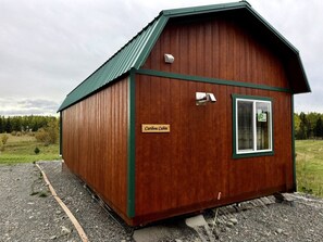 A small, single-story cabin with a green roof and a nameplate reading 'Caribou Cabin.'