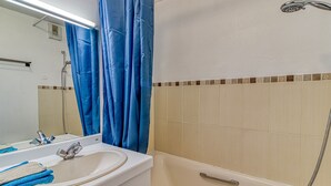 A bathroom with a sink, mirror, blue shower curtain, and a bathtub. - Les Goélands - Vue mer à moins d'1 Km de la plage (Bray-Dunes)
