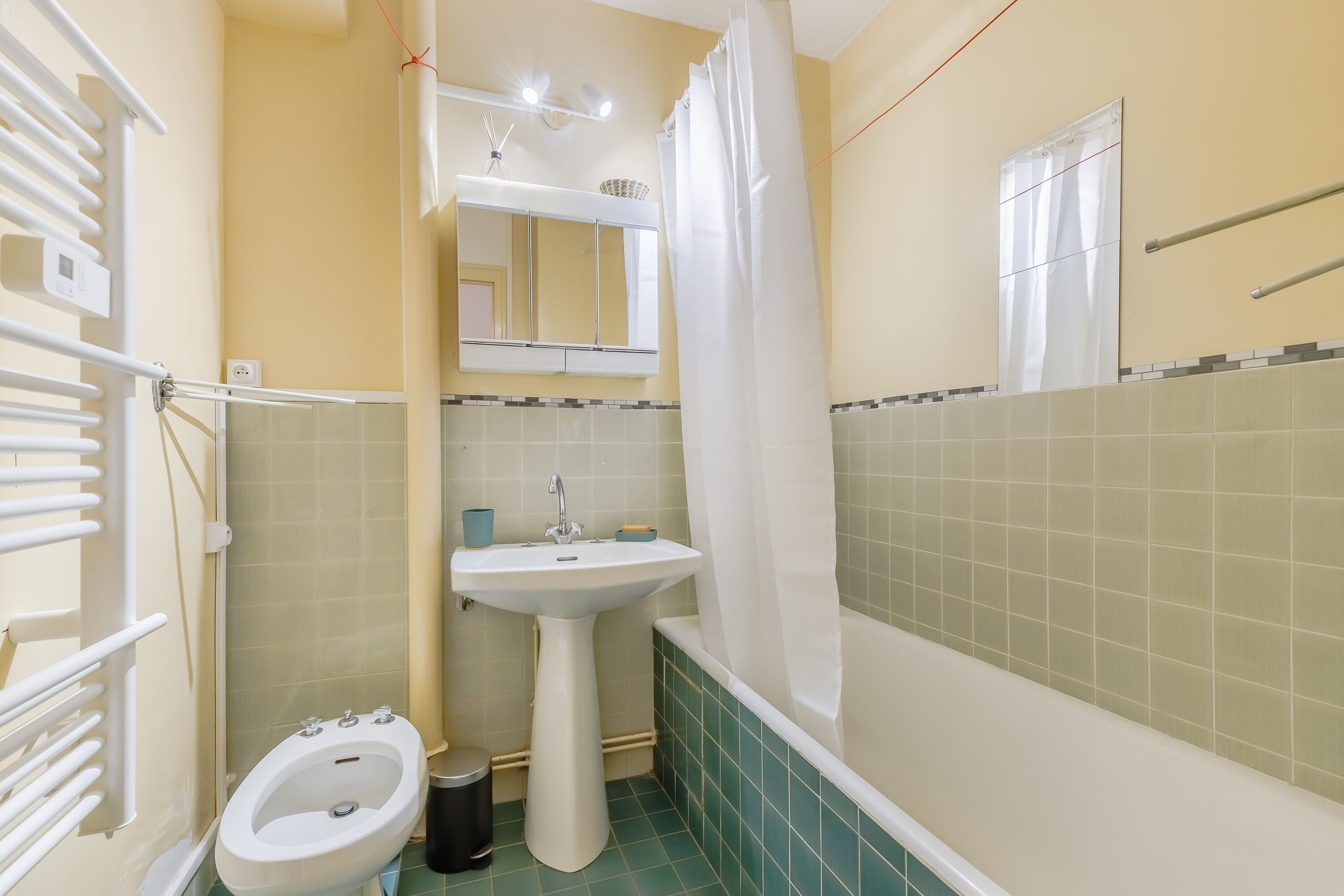 Een badkamer met een wastafel op een voetstuk, een toilet, een bad en een douchetoilet.