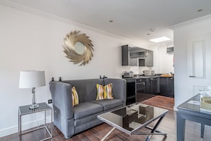 Un salon moderne avec un canapé gris, une table basse en verre et un miroir décoratif accroché au mur.