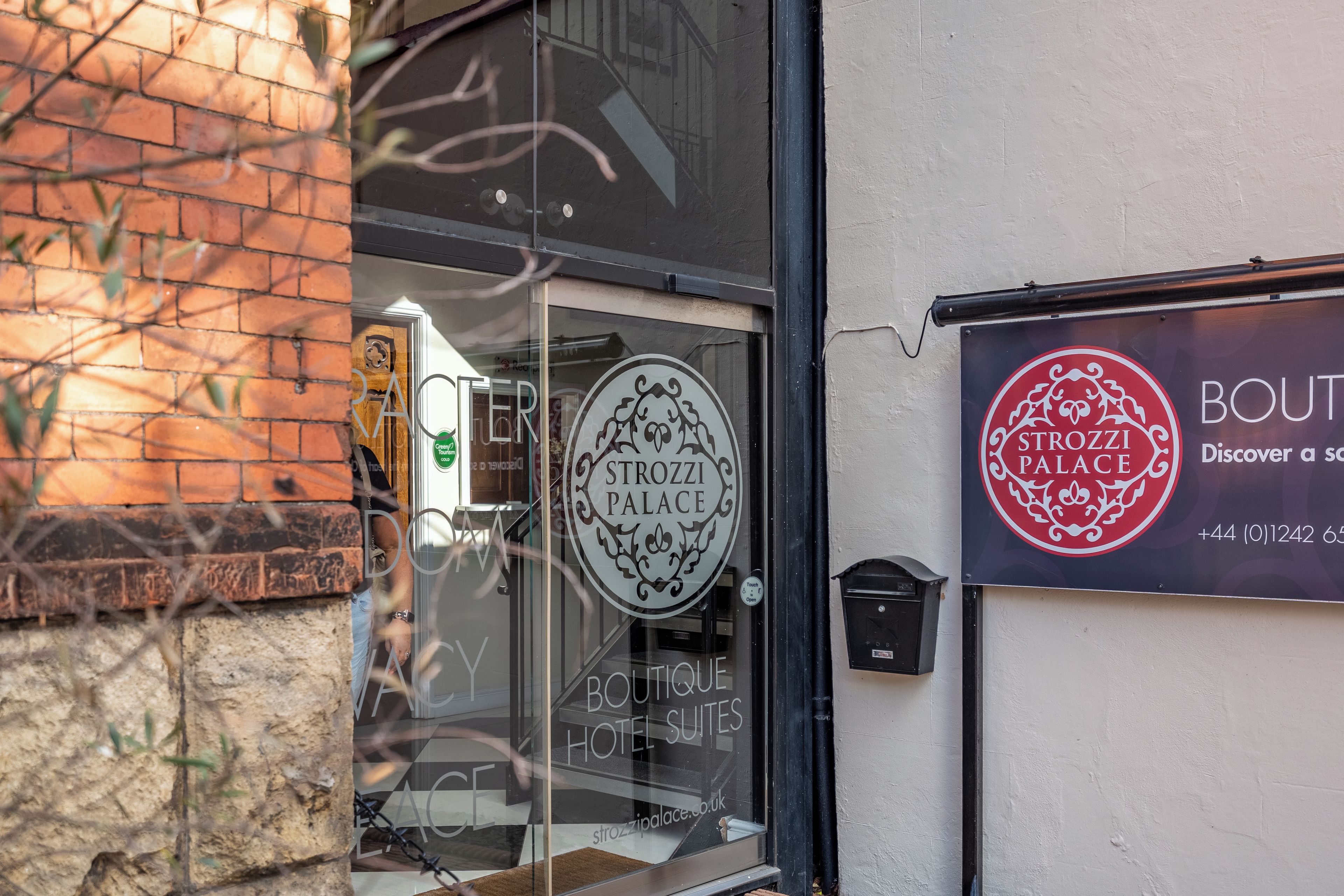 A boutique hotel entrance with a glass door and a sign for 'Strozzi Palace Boutique Hotel Suites'.