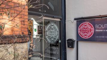 A boutique hotel entrance with a glass door and a sign for 'Strozzi Palace Boutique Hotel Suites'.