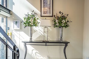 A table with two vases of flowers, a framed picture on the wall, and a lamp. - Strozzi Palace Luxury Boutique Suites (Cheltenham)