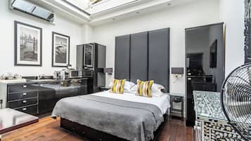 A modern bedroom with a large bed, a built-in wardrobe, a desk, and a dining table.