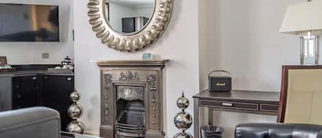 A living room with a fireplace, a television, and a leather armchair.