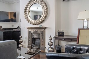 A living room with a fireplace, a television, and a leather armchair. - Strozzi Palace Luxury Boutique Suites (Cheltenham)