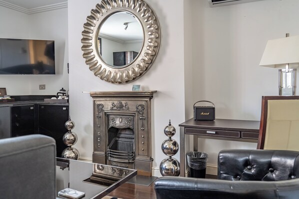 A living room with a fireplace, a television, and a leather armchair. - Strozzi Palace Luxury Boutique Suites (Cheltenham)