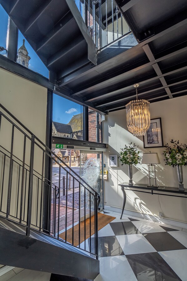 A staircase with a black railing leading to an upper floor, a chandelier, and a view of a building with a dome. - Strozzi Palace Luxury Boutique Suites (Cheltenham)