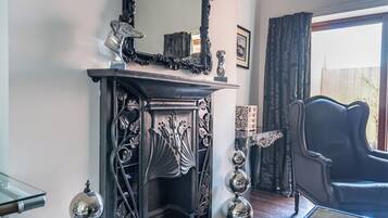 A room with a fireplace, a black leather armchair, and a glass coffee table.