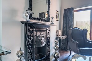 Una habitación con chimenea, un sillón de cuero negro y una mesa de centro de vidrio.