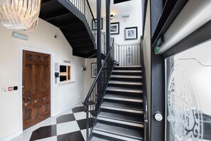 A staircase with a black and white checkered floor, a wooden door with a reception sign, and a wall-mounted phone. - Strozzi Palace Luxury Boutique Suites (Cheltenham)