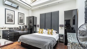 Een moderne slaapkamer met een groot bed, nachtkastjes, een inbouwkast en een dakraam.