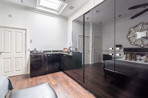 A modern kitchen with dark cabinetry, a built-in island, and a large mirror. - Strozzi Palace Luxury Boutique Suites (Cheltenham)
