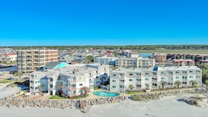 Zona residencial costera con edificios de varios pisos, una piscina y una playa al frente.