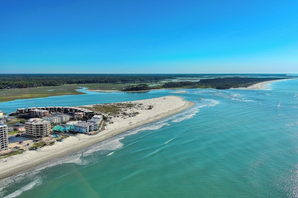 Vista aérea de una zona costera con edificios a lo largo de la orilla, una playa y un río o bahía.