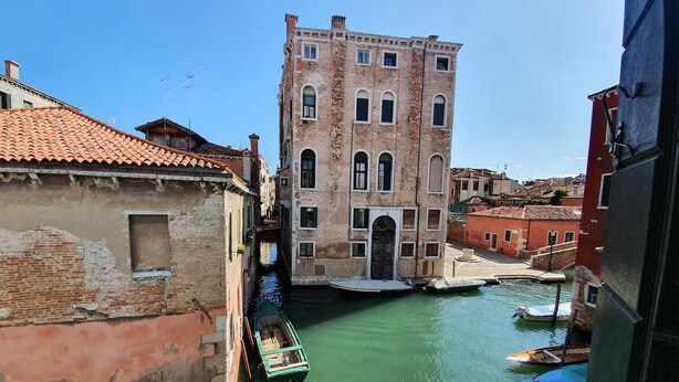 A narrow canal with a historic building and a boat docked on the right. - VENICE SANCTUARY: 4-BEDROOM APARTMENT, CENTRAL, CANAL VIEWS WITH 2 TERRACE  (Venezia)