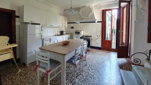 A kitchen with white cabinets, a dining table with chairs, a stove, and a microwave. - VENICE SANCTUARY: 4-BEDROOM APARTMENT, CENTRAL, CANAL VIEWS WITH 2 TERRACE  (Venezia)