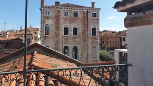 A historic building with a tiled roof and brick facade, surrounded by other buildings. - VENICE SANCTUARY: 4-BEDROOM APARTMENT, CENTRAL, CANAL VIEWS WITH 2 TERRACE  (Venezia)