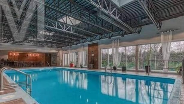Una piscina interior amb vista clara a l'estructura del sostre i una zona de bar al fons.