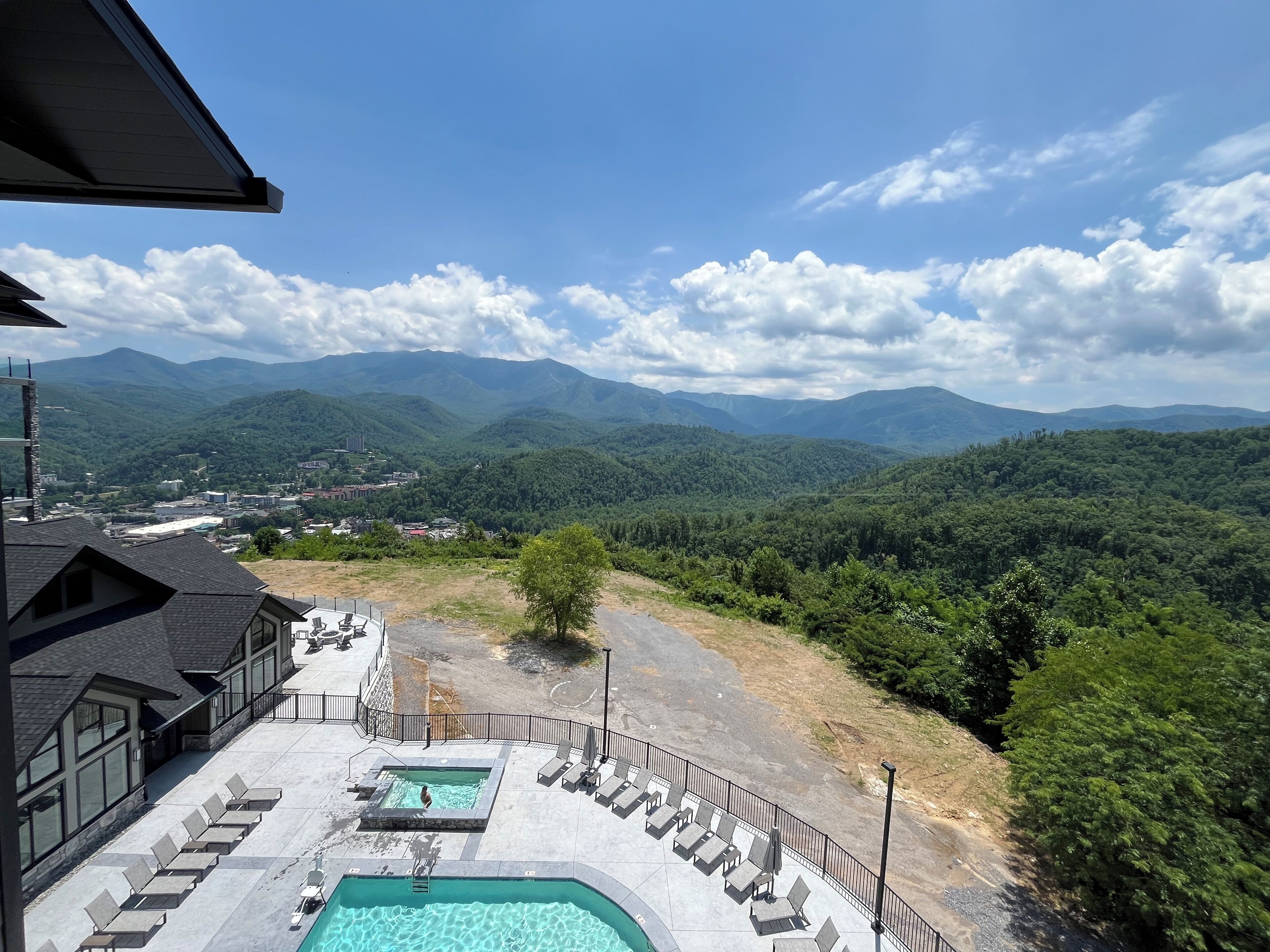 Ein Hotel mit Poolbereich, Sitzgelegenheiten im Freien und Blick auf Berge.