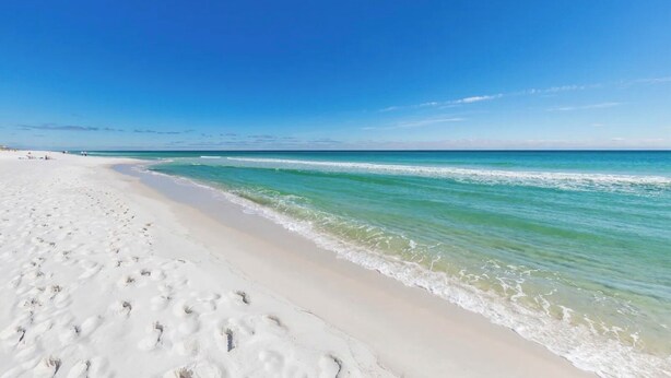 Une plage de sable blanc bordée d’une eau d’un bleu limpide.