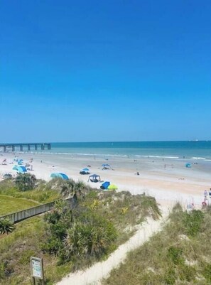 Une plage avec des tentes et une jetée en arrière-plan.