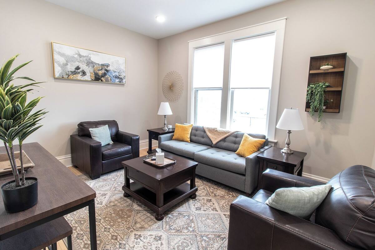 A living room with a sofa, armchairs, a coffee table, and a potted plant.