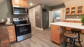 A modern kitchen with wooden cabinets, stainless steel appliances, and a central island with stools.