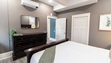 A bedroom with a bed, dresser, mirror, and white doors.
